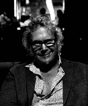 Profile photograph of author Bromme sitting in chair, casually dressed and looking at viewer.